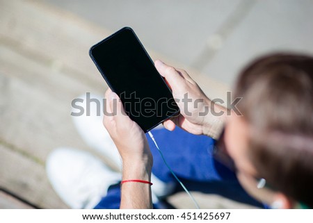 Closeup of cellphone display in male hands outdoors on the street. Man using mobile smartphone.