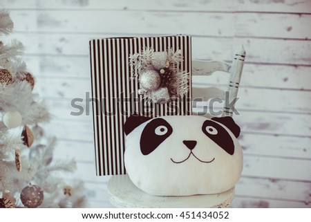 A pillow in the form of panda lies on the white wooden chair
