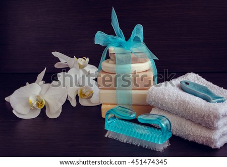 Composition of spa treatment on dark wooden background. Spa and wellness setting in white ans blue colors with natural homemade soaps, flowers and soft towels. Selective focus. 