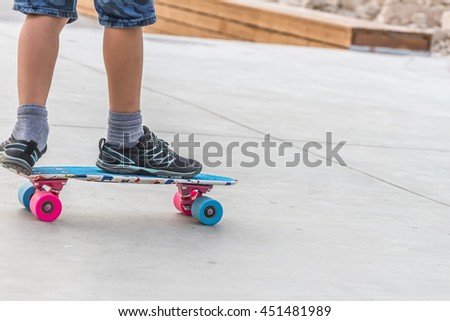 close up of boy's feet standing on modern short cruiser skateboard on asphalt background