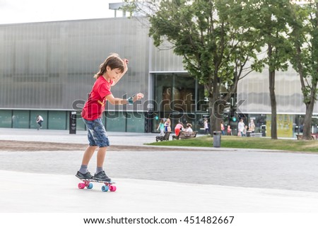 outdoor portrait of young smiling teenager boy riding short modern cruiser skateboard, urban background