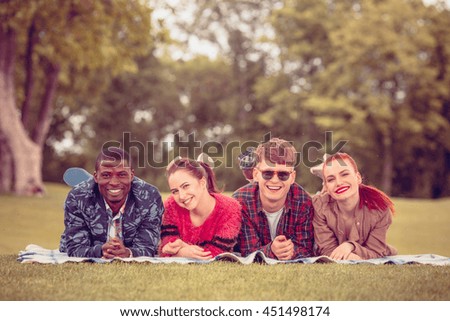 Toned. Beautiful people spending their free time with nature. Picture of happy couples smiling to camera while lying on picnic rug on picnic.