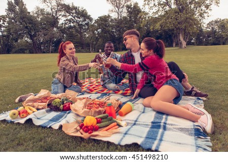 Toned. Picture of best friends or two couples drinking alcohol drinks while resting and relaxing on picnic. People enjoying their free time with nature.