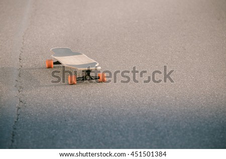 Longboard with orange wheels on the asphalt.