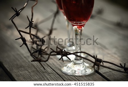 Rusty barbed wire and glasses with red wine on a table.  Alcoholic dependence.