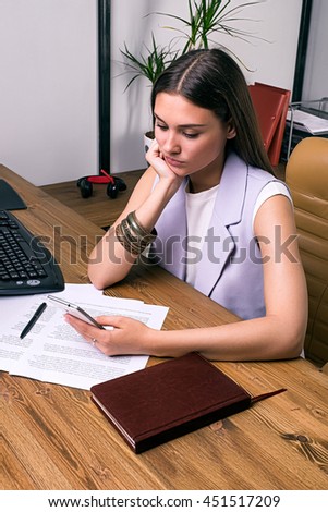 Portrait of young businesswoman texting over smartphone at office table