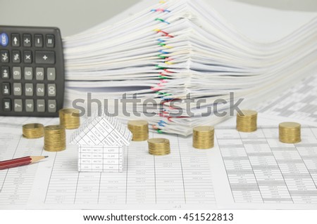 House on finance account have blur pencil and pile of gold coins with calculator place vertical and pile overload paperwork of report and receipt with colorful paperclip on white background.