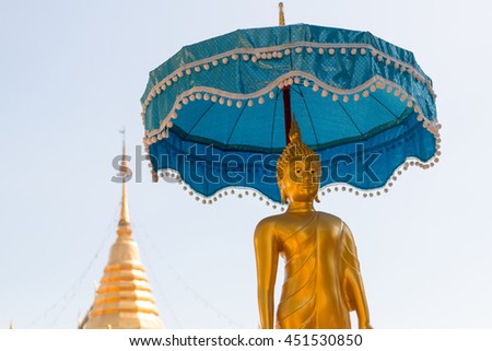 Ancient golden Buddha statue under an umbrella in Thai temple