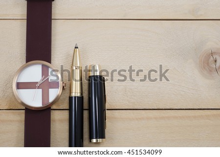 wrist watch and pen on wooden background