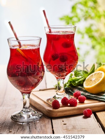 On wooden boards are ice cold beverage two glasses with red berries lemon cocktail . Alcohol country cocktail beverage number ninety seven with leaf mint. Outdoor country cocktail .