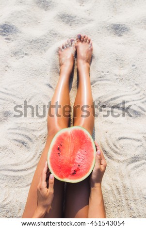 Woman with half of watermelon on beach
