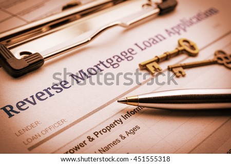 Vintage color style : Blue ballpoint pen, two brass keys and a reverse mortgage loan application on a clipboard. A form is waiting to be filled by a homeowner who want to turn their asset into cash.