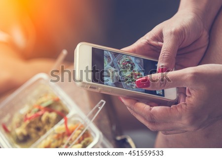 Close up of woman hands clicking picture of food. Woman using smartphone for food photography.female hands taking photo of pasta curry lunch box and chiken with smart phone.