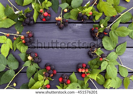 Shape of heart made of blackberry on a black wooden background with free space center. Top view. The picture on Valentine Day.