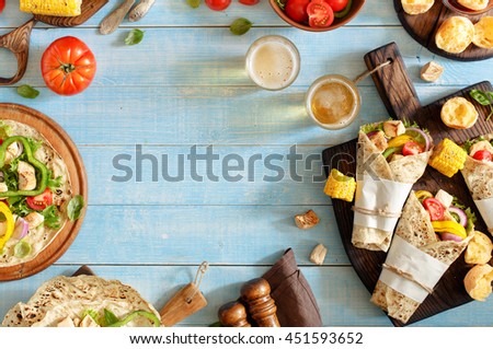 Tortilla with grilled chicken fillet, beer and vegetables on a blue wooden table with copy space. Top view. Outdoors Food Concept