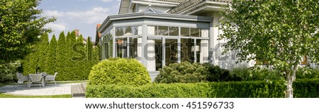 Spacious orangery in a large villa surrounded by a vast garden with hedge and well-groomed trees and grass Royalty-Free Stock Photo #451596733