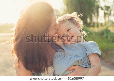 Mother kissing toddler girl in hands