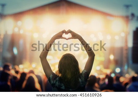 Girl making a heart-shape symbol for her favorite band. Royalty-Free Stock Photo #451610926
