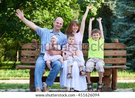 happy family portrait on outdoor, group of five people sit on wooden bench in city park, summer season, child and parent