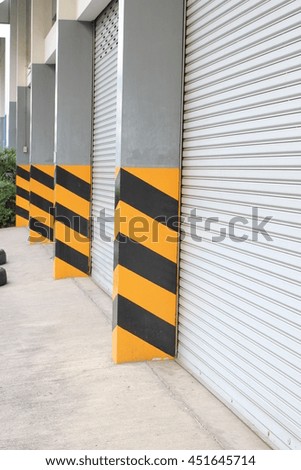 Traffic barrier in front of factory with Steel door, Black and yellow traffic sign 