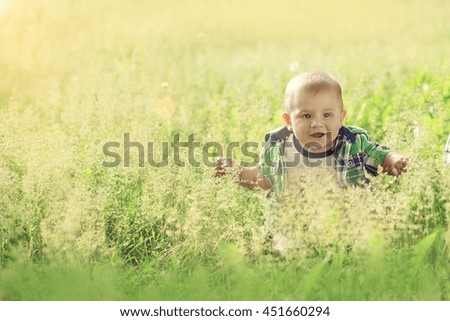 little baby boy sitting summer outdoors grass in sun and enjoy the warmth and laughs