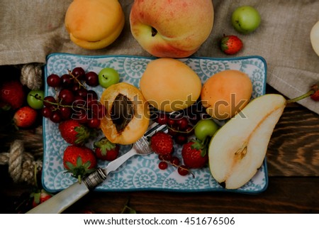 A glamour picture of fresh summer fruits as red currant, green plum, pear, strawberry, apricot and peach on wooden table background
