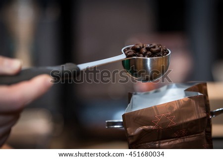 Side view of fresh roasted coffee beans in an espresso fliter in a man's hand  Royalty-Free Stock Photo #451680034
