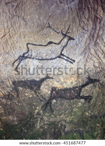 Black carbon paint of deer on sandstone wall, copy of prehistoric picture. Abstract children art in sandstone cave.