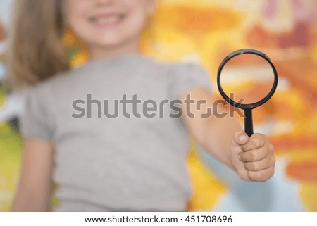 The little girl on the background of the world map with a magnifying glass in hand