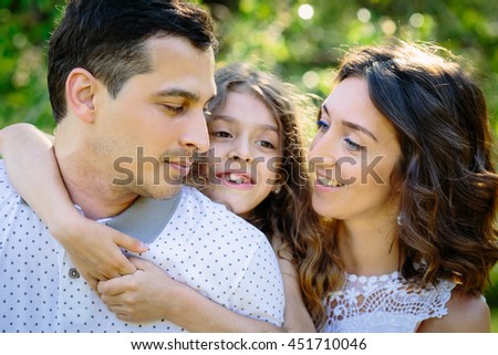 Young happy family three daughter mother and father hug each other in the park