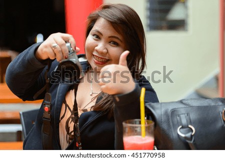 Fat woman photographing and giving thumbs up