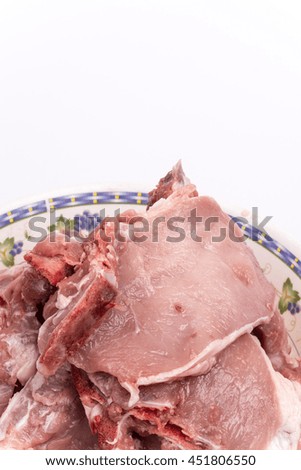Pile of raw pork chops in the bowl over white background