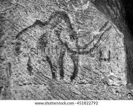 Abstract children art in sandstone cave. Black carbon mammoth paint of human hunting on sandstone wall, copy of prehistoric picture.