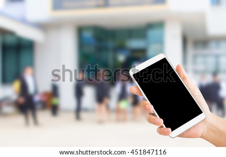 woman use mobile phone and blurred image of people protest in front of government office