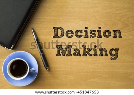 Decision making words writing on wooden desk with notebook, pen and cup of coffee, Top view conceptual.