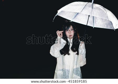Charming Asian girl  with umbrella and raincoat at night