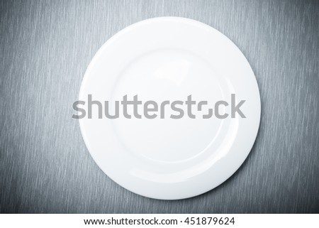 Empty white plate on grey napkin, top view. Toned.