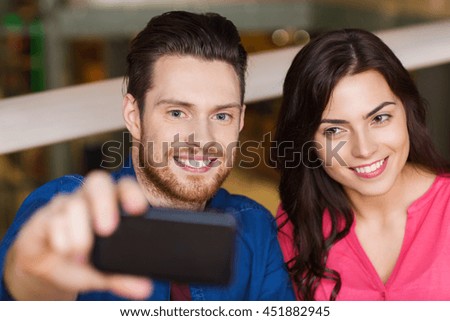 leisure, technology, date, people and holidays concept - happy couple taking selfie by smartphone at restaurant