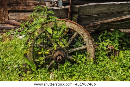 Old wooden wheel near log barn


