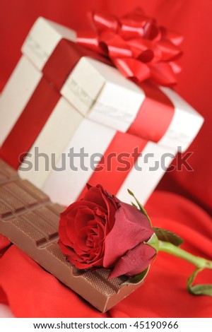 beautiful red rose, gift and chocolate  on red close up