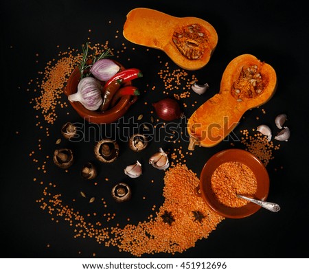 Raw vegetables and kitchen utensils on a black background. Artistic composition