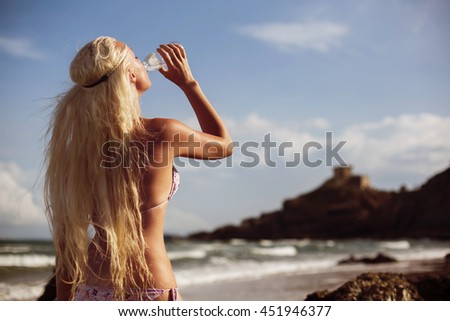 Fashion blond sporty woman in bikini drinking fresh clean water from the bottle. Hot summer day, activity outdoor, healthy lifestyle 
