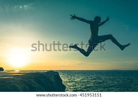 Man jumping over a cliff into the sea on sunset in Koh Phangan island, Thailand. Vintage effect. No fear, courage, brave, dare concept. Three out of three series Royalty-Free Stock Photo #451953151
