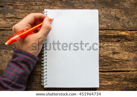 left-handed man writes in a notebook Royalty-Free Stock Photo #451964734
