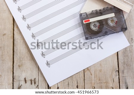 Sheet music, tape cassette on wooden table, flat lay
