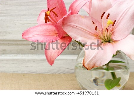 Romantic composition with bouquet of fresh pink lily in a glass ball. Concept for birthday, valentine, mothers day, anniversary. Floral decor. Copy space