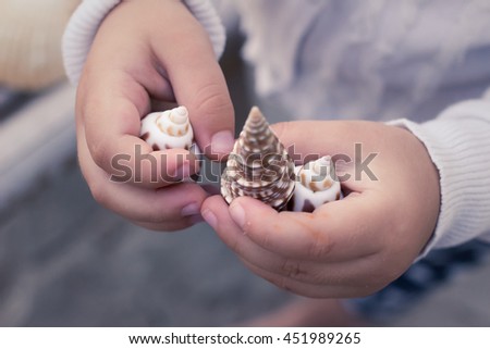 Child's hands with beautiful seashell. Toned image, shallow depth of field. Royalty-Free Stock Photo #451989265