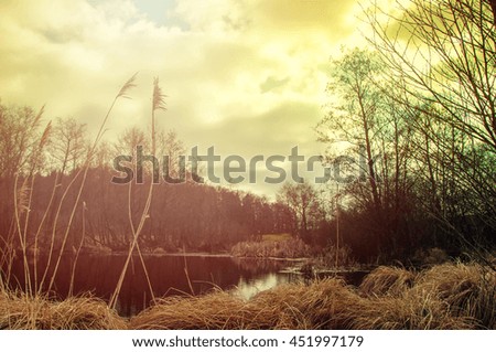 Winter or early spring landscape of field with raised hide under cloudy sky. Sad landscape