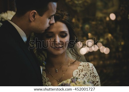 A dark picture of newlyweds kissing in the front of old icons