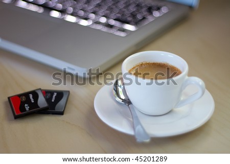 Espresso in a plain white porcelain cup on a desk next to notebook with shallow depth of field.